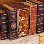Minicity Painter's Day at Dusk DIY book nook displayed between books with detailed artist's studio interior and warm illumination