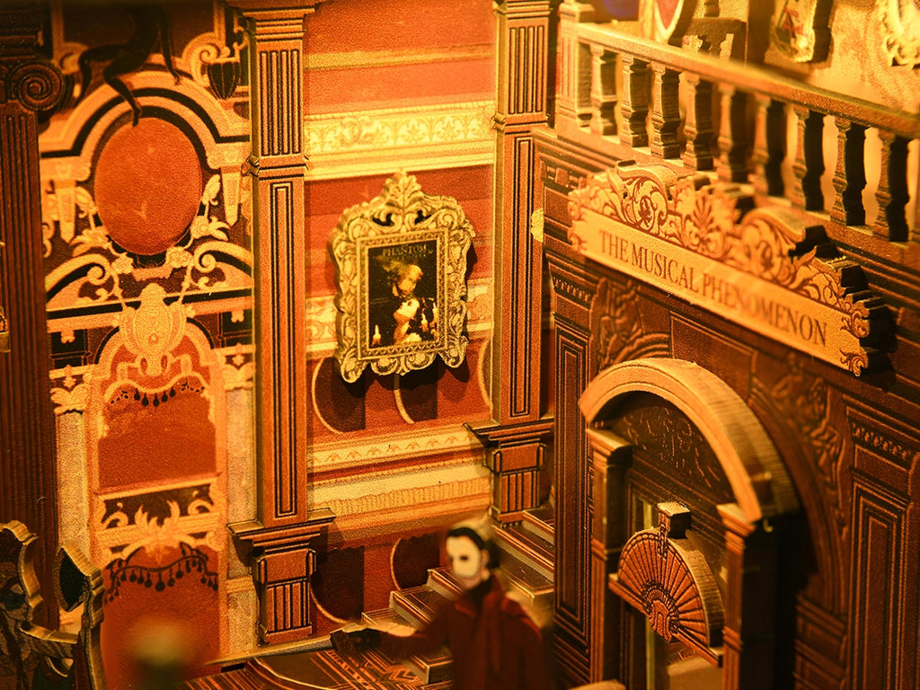 Detailed view of the Phantom of the Opera miniature theatre showing ornate wall panels, a framed portrait, carved columns and a masked character