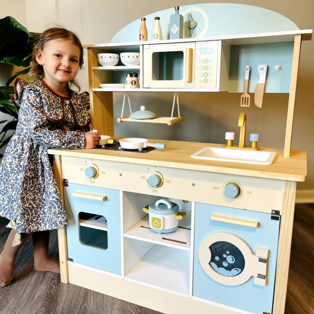 ROBUD Dream Kids Play Kitchen with a child preparing pretend food using the stovetop, cookware and kitchen storage