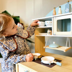 ROBUD Dream Wooden Play Kitchen with child organising bowls and preparing pretend food on the stovetop
