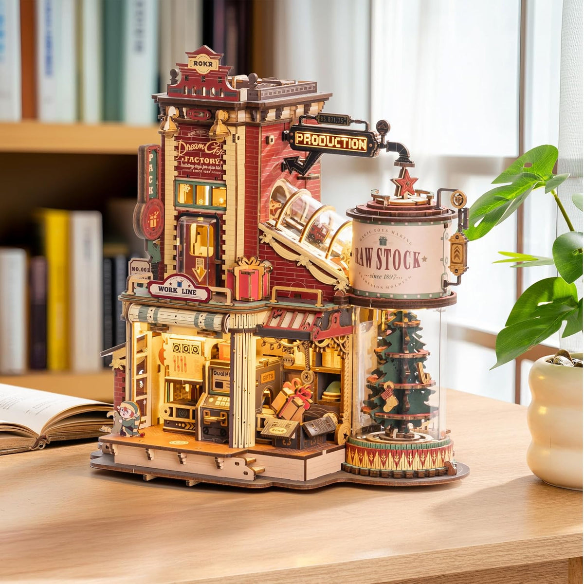 ROKR Dream Gift Factory wooden mechanical model displayed on a desk with moving conveyor system, packaging station and miniature Christmas tree
