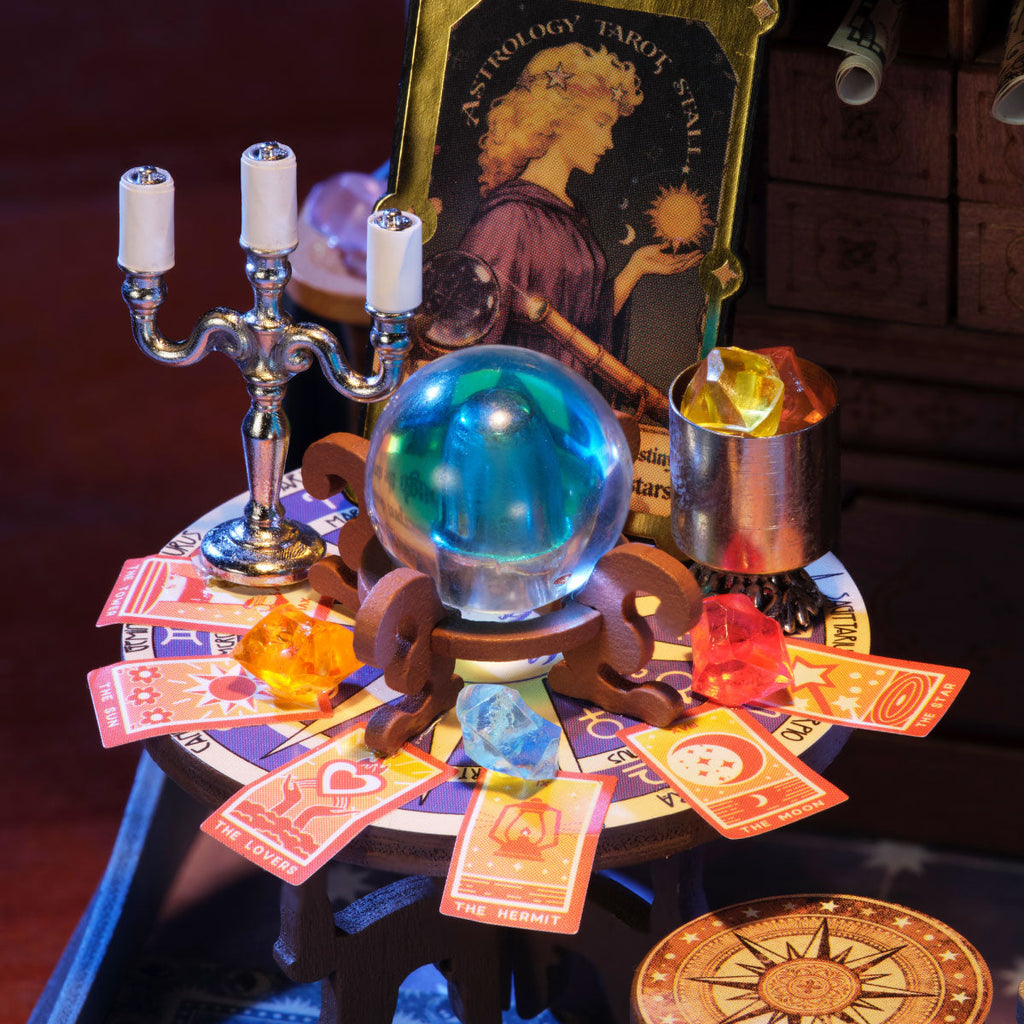 Rolife Astral Dome close-up of the tarot reading table with a blue crystal ball, colourful gemstones, tarot cards, silver candle holder and astrology artwork