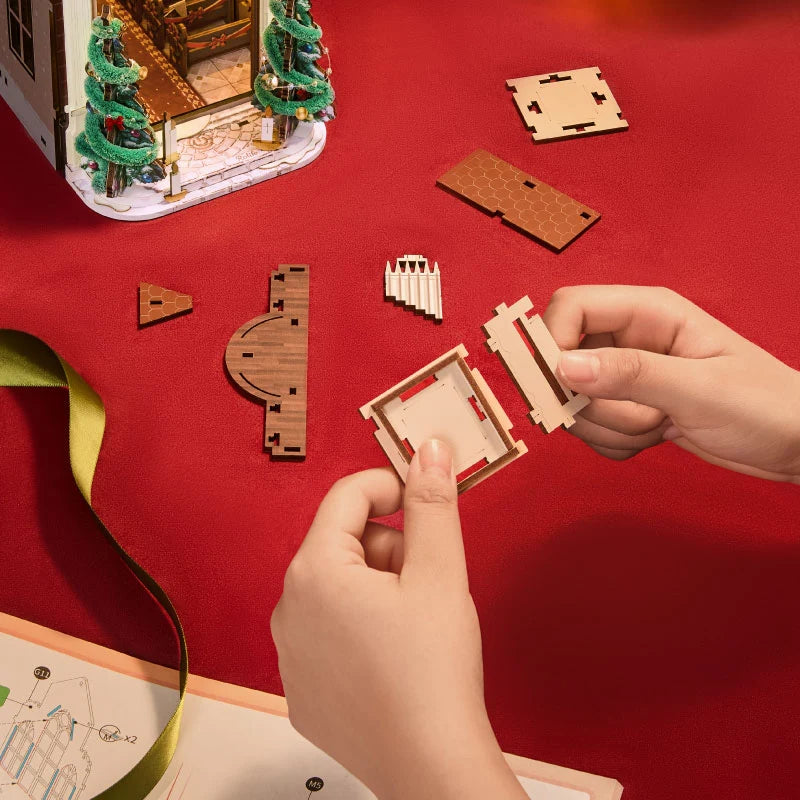 Rolife Caroling Cathedral DIY book nook assembly with hands fitting precision-cut pieces and illustrated instructions on a red work surface