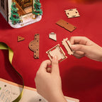Rolife Caroling Cathedral DIY book nook assembly with hands fitting precision-cut pieces and illustrated instructions on a red work surface
