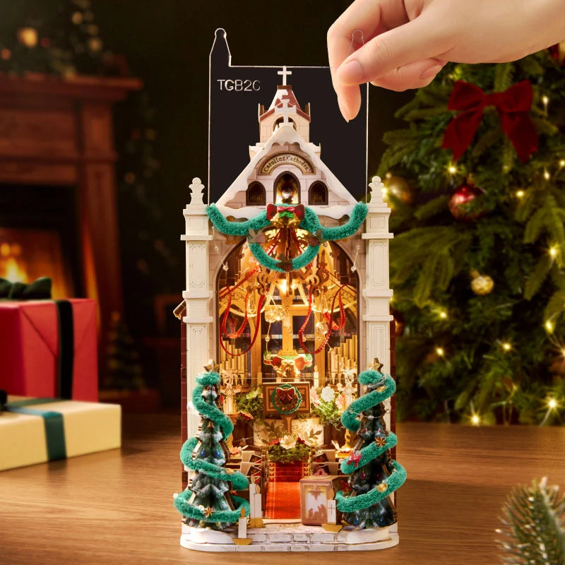 Rolife Caroling Cathedral book nook with its transparent protective dust cover being fitted over the illuminated miniature cathedral