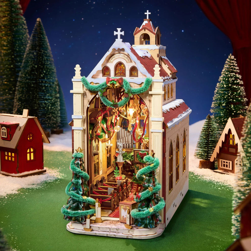 Rolife Caroling Cathedral illuminated miniature church displayed in a snowy Christmas village setting with festive trees and small houses