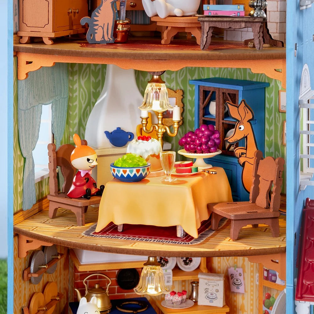 Rolife Moominhouse miniature dining room with Little My, a yellow tablecloth, colourful food, fruit, wooden chairs and decorative lighting