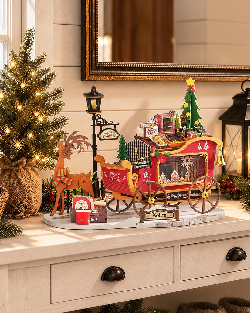 Rolife Reindeer Express miniature Christmas sleigh displayed on a white console table beside a decorated Christmas tree and festive lantern