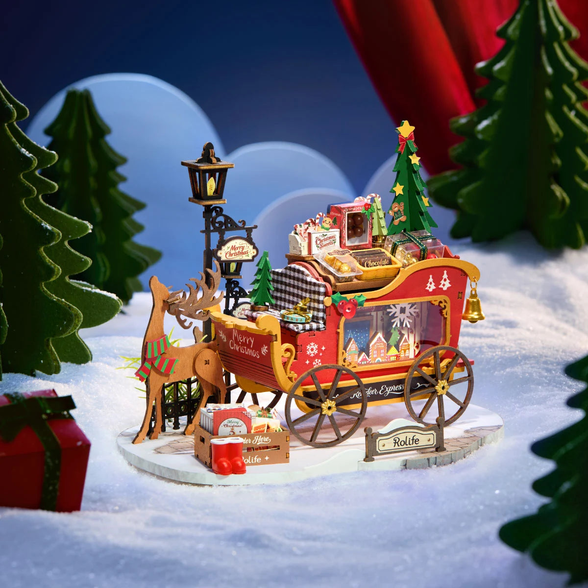 Rolife Reindeer Express wooden reindeer and red Christmas sleigh displayed on a snowy base against a blue winter backdrop with miniature evergreen trees