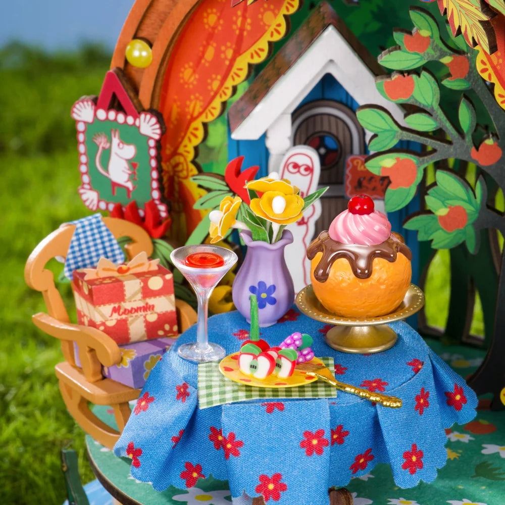 Rolife Snorkmaiden's Garden Party close-up showing miniature cakes, drinks, fruit, flowers and a blue floral tablecloth