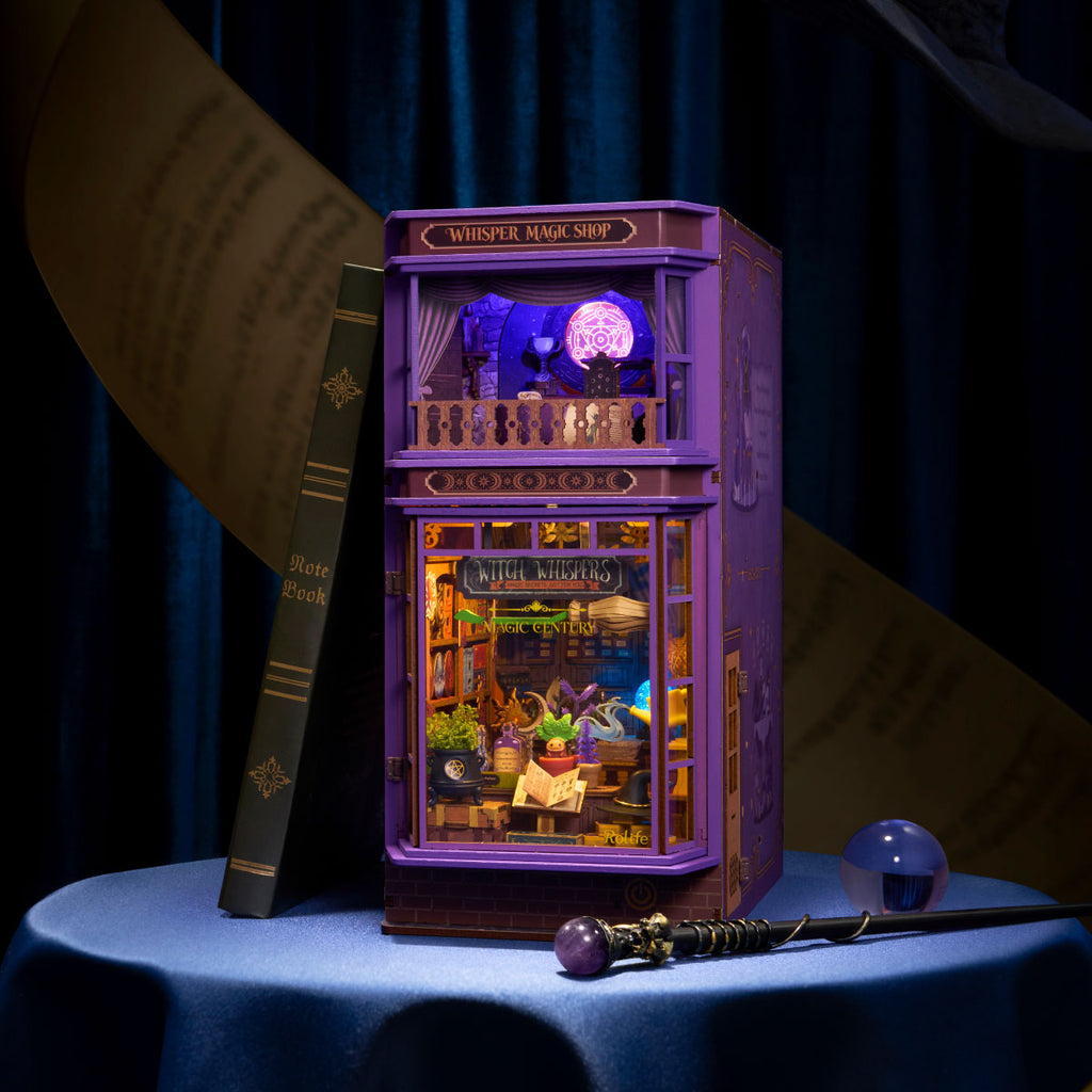 Rolife Whisper Magic Shop DIY book nook illuminated with purple and warm ambient lighting beside fantasy books