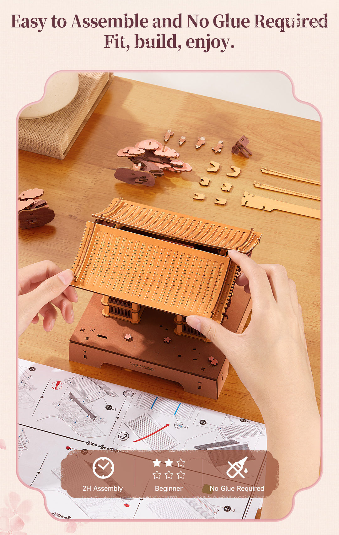 Hands assembling the curved wooden roof of the Rowood Sacred Sakura Temple puzzle with illustrated instructions and loose wooden components on a table